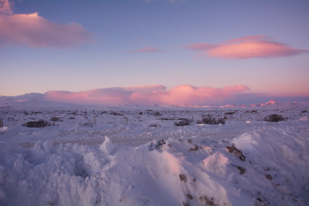 paesaggio islandese innevato con cielo al tramonto di colore rosa e viola