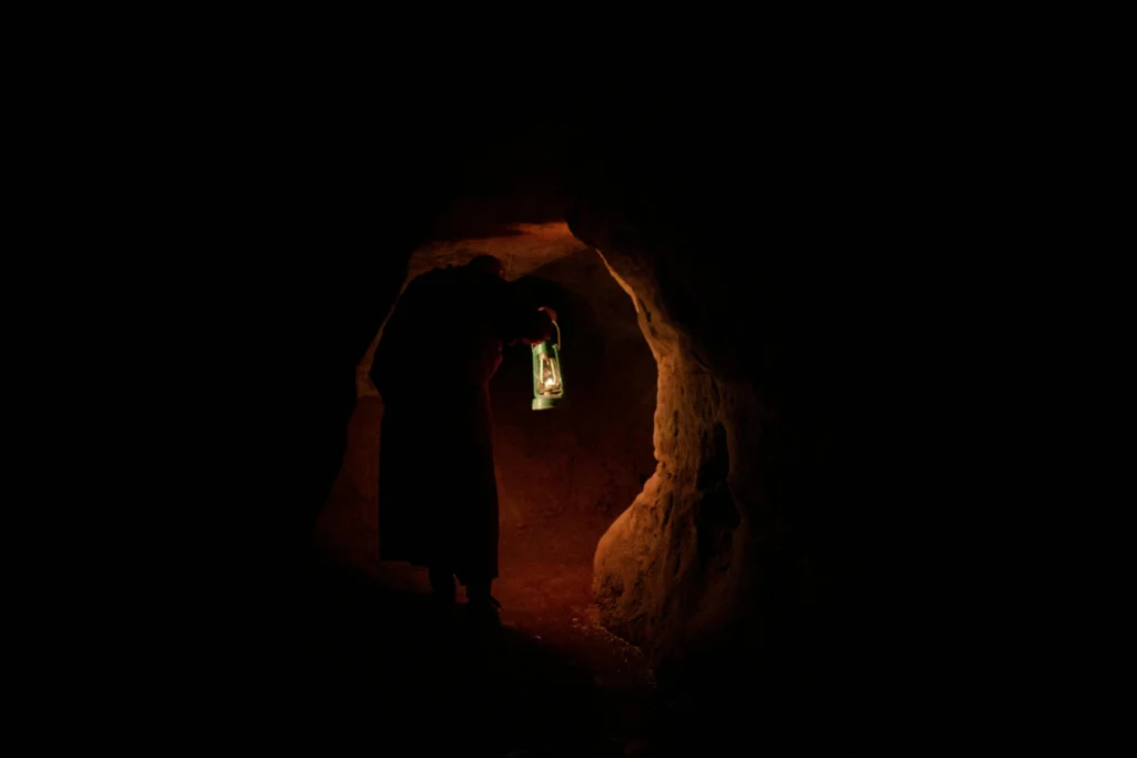 Persona dentro una grotta buia con in mano una lampada antica
